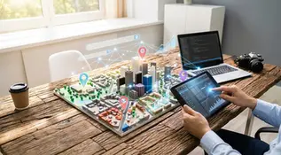 Modelo de cidade em 3D sobre mesa, com tablet e laptop, marcadores de localização e gráficos digitais.